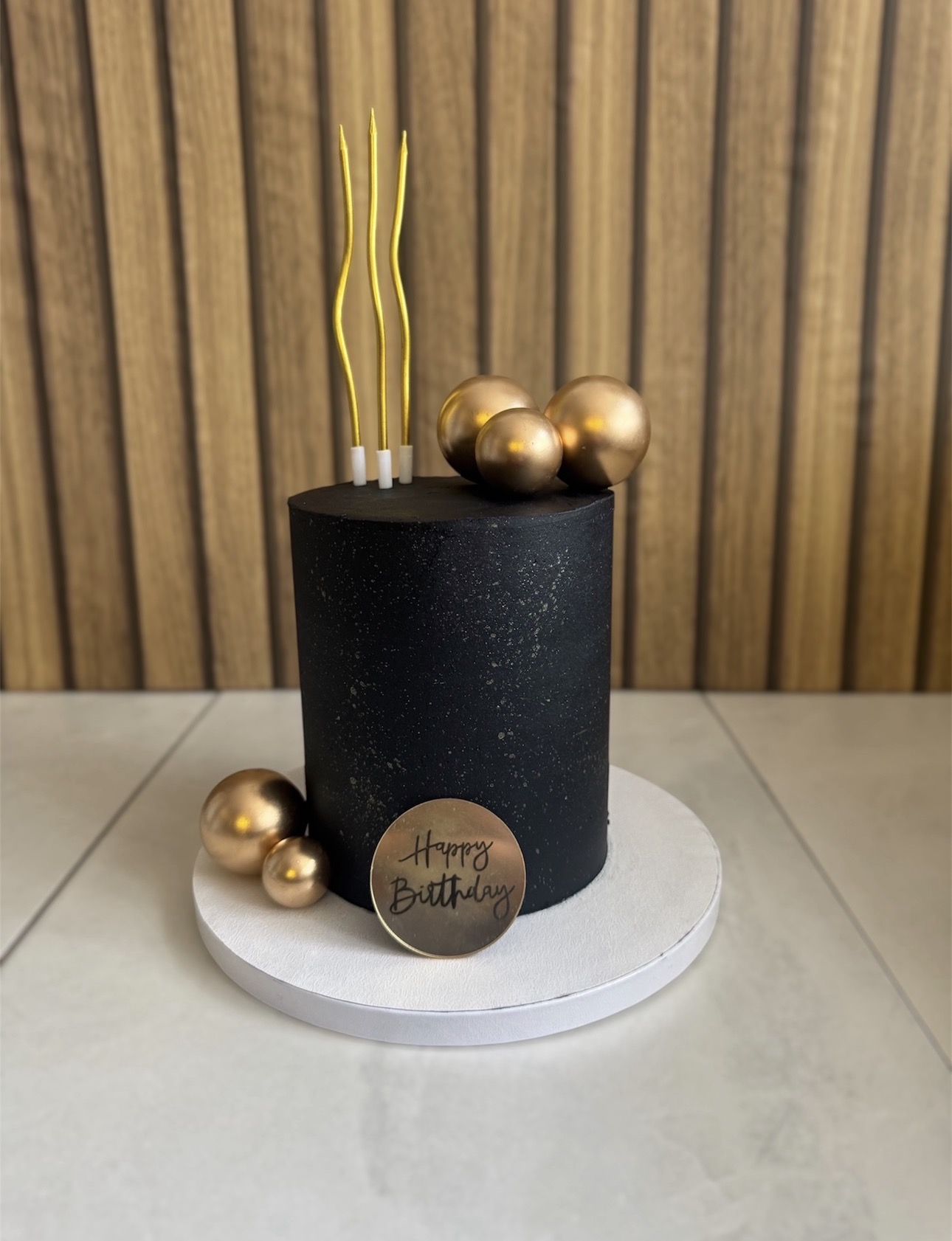 Black and gold birthday cake with gold spheres